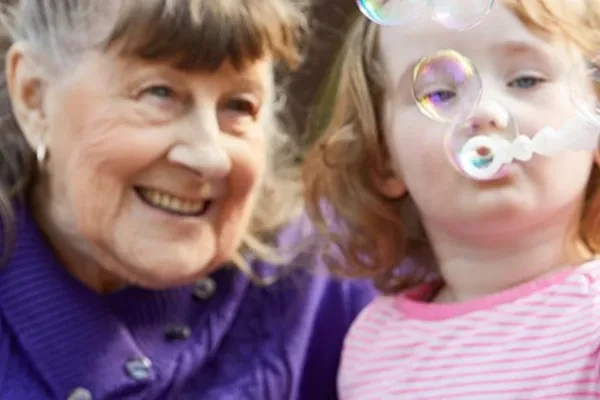 A resident laughing as a young visitor blows bubbles