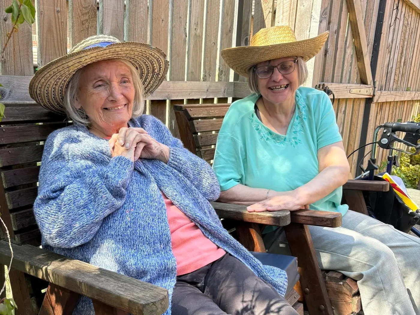 Two residents sharing a smile in the garden in their sun hats
