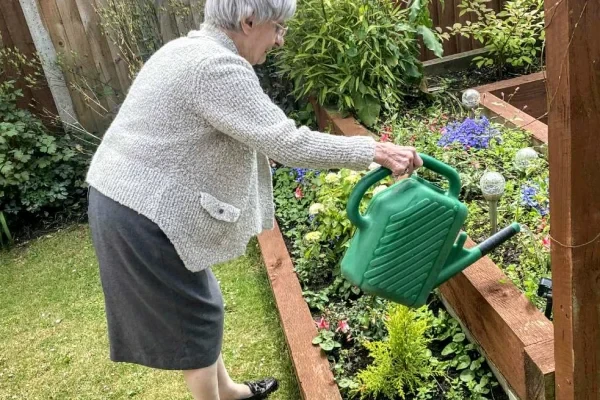 A resident watering the raised flower beds