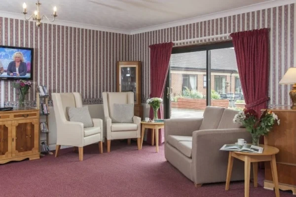 A homely lounge with armchairs, plants and fresh flowers